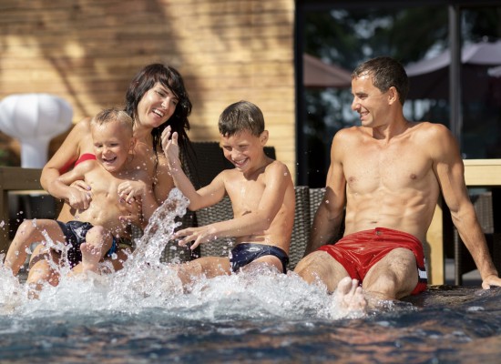 Padres e hijos jugando en el agua de la piscina